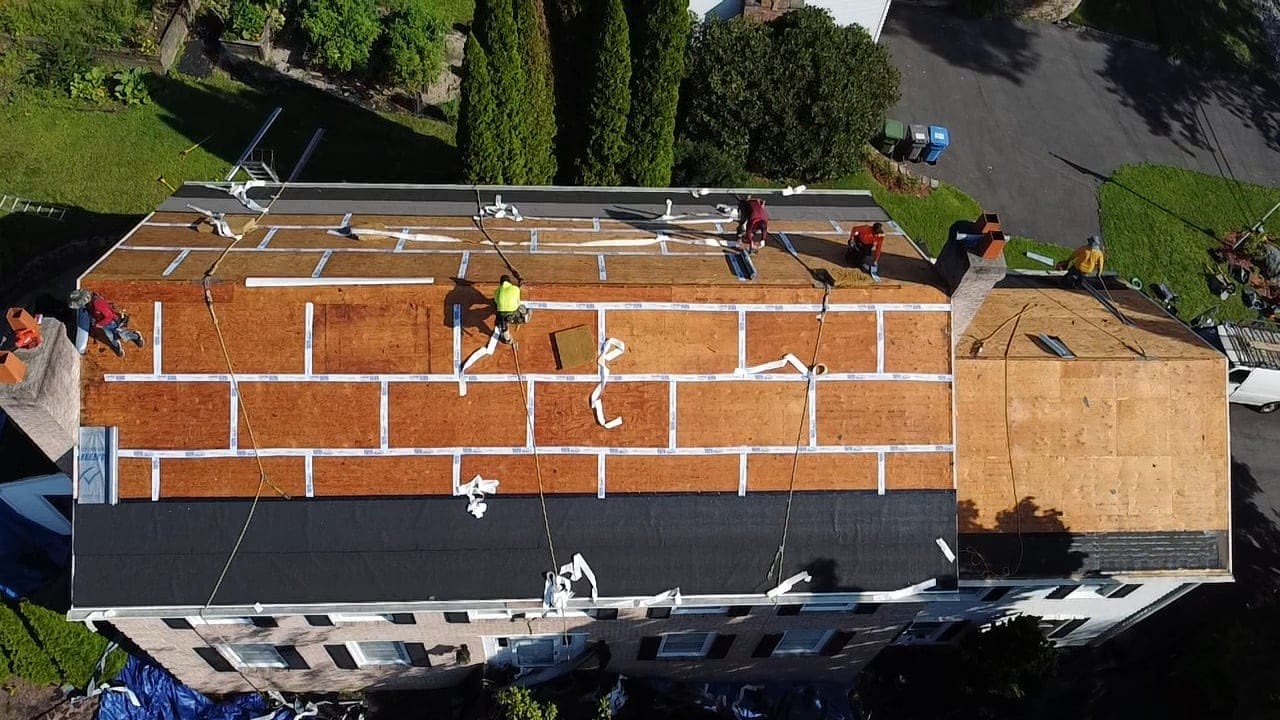 Aerial view of a tear-off in progress on a brick building, decking exposed