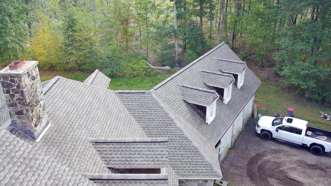 Aerial view of a finished roof with a Genesis General Construction truck parked in the driveway