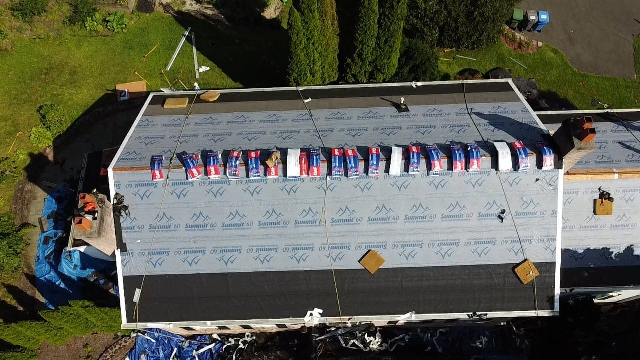 Aerial view of underlayment being installed across a low-slope roof