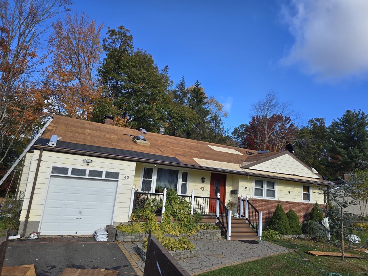 Ground-level view of a finished colonial home with new roof under a blue sky